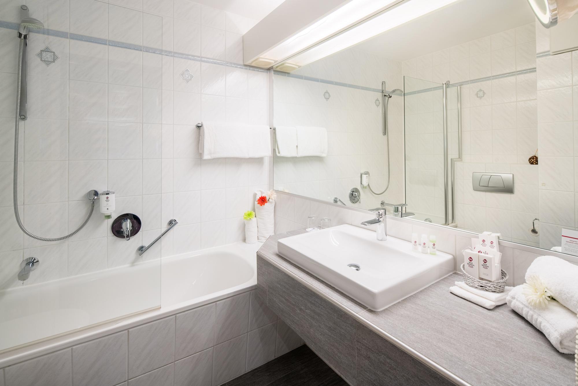 Modernes Bad mit Badewanne, beleuchtetem Spiegel und hellen Fliesen für ein sauberes Ambiente.