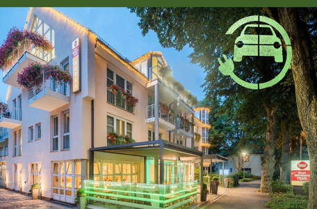 Modernes Hotel mit Balkonen, „Best Western Plus“-Schild, E-Ladesymbol und beleuchtetem Außenbereich