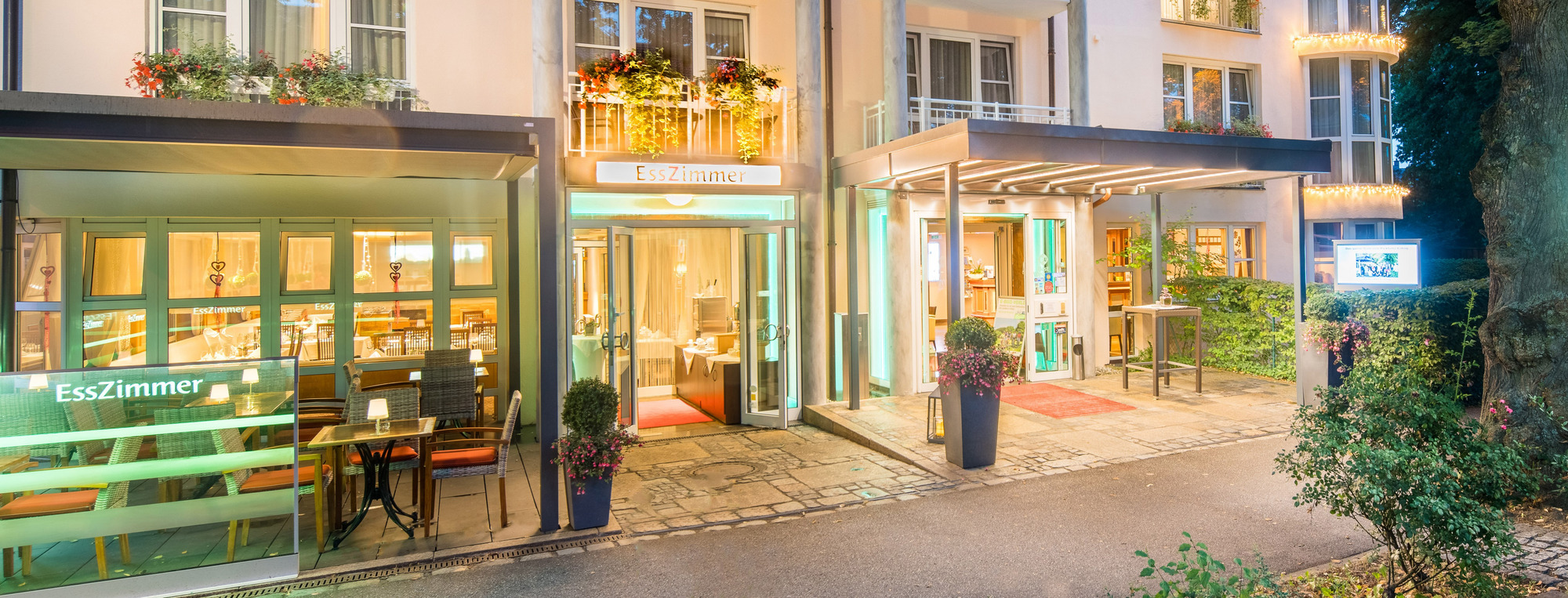 Modernes Gebäude mit Balkonen, Caféterrasse im Grünen bei Nacht